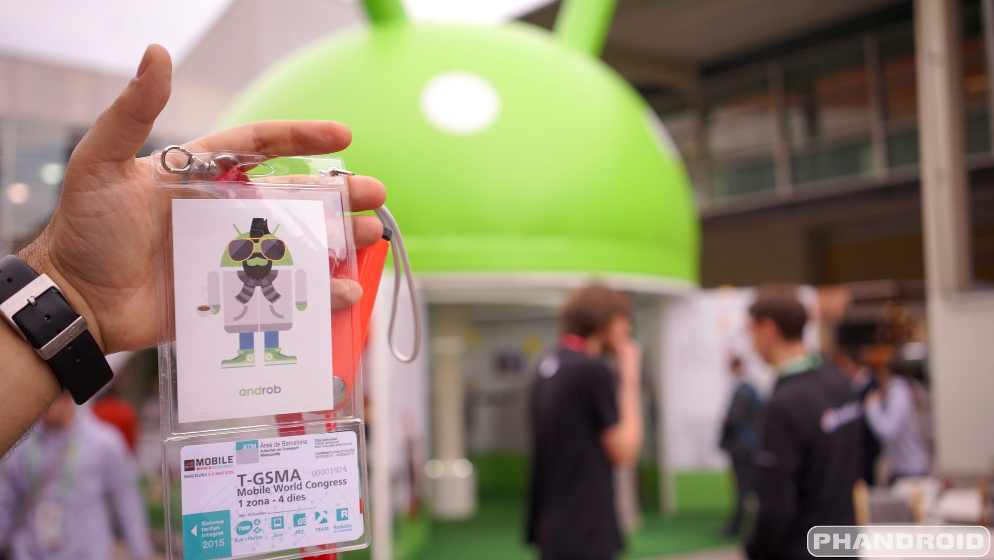 A delegate holding up a lanyard with a freshly printed personalised Android avatar sticker, the Android dome behind