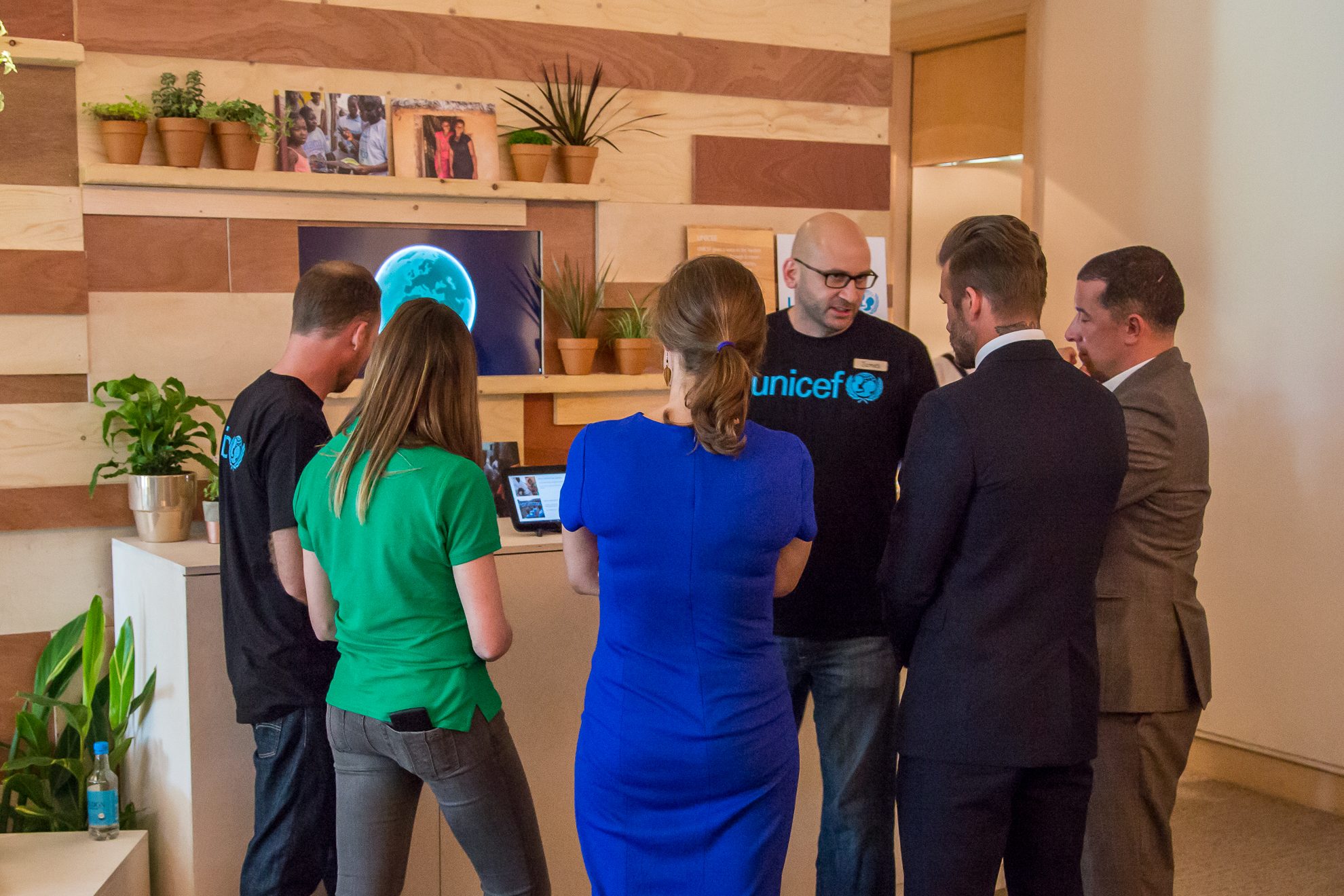 Guests including David Beckham gathered around the UNICEF installation while an ambassador demonstrates the globe